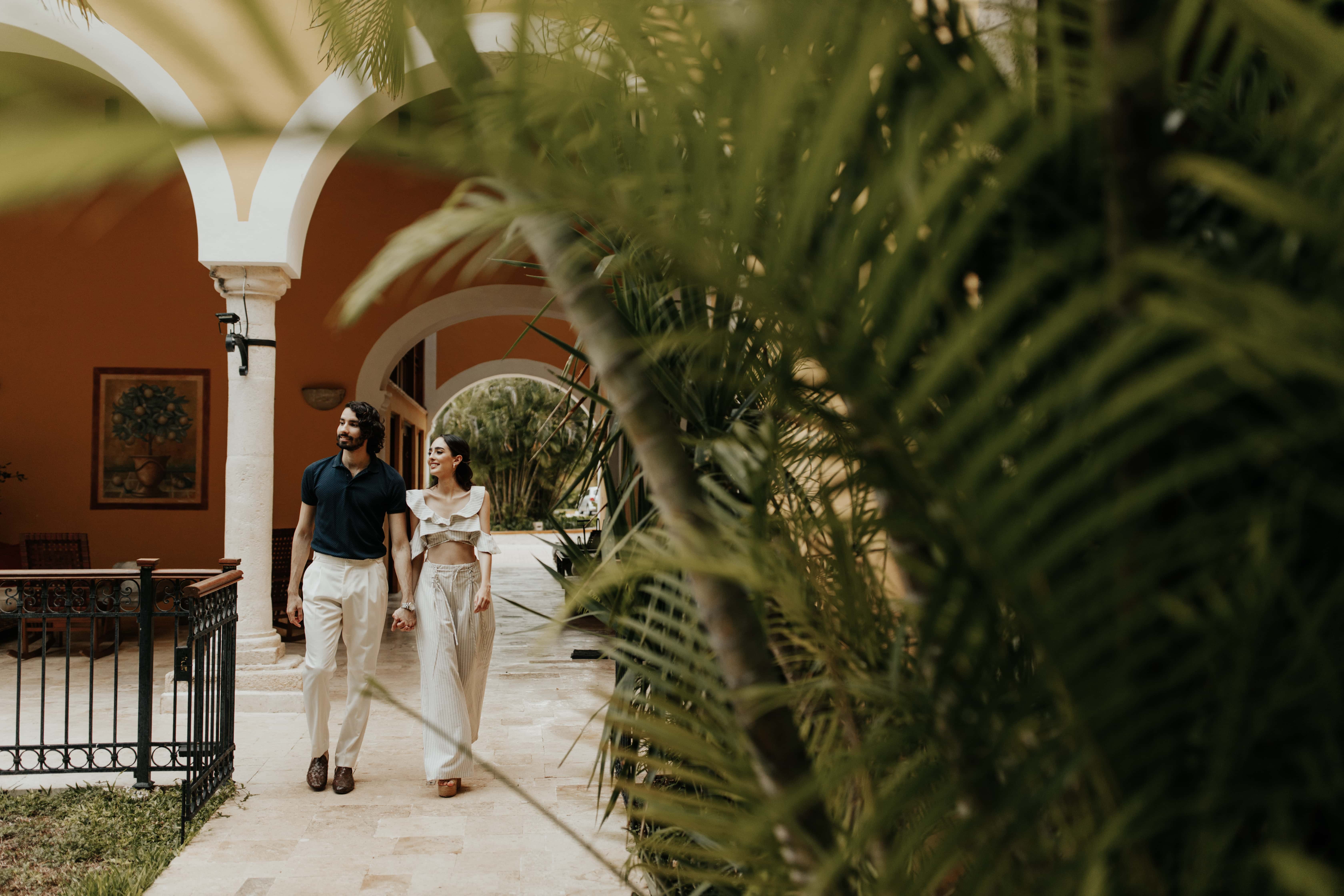 Couple walking through lush, arched courtyard at Hacienda Xcanatun, Angsana Heritage Collection.